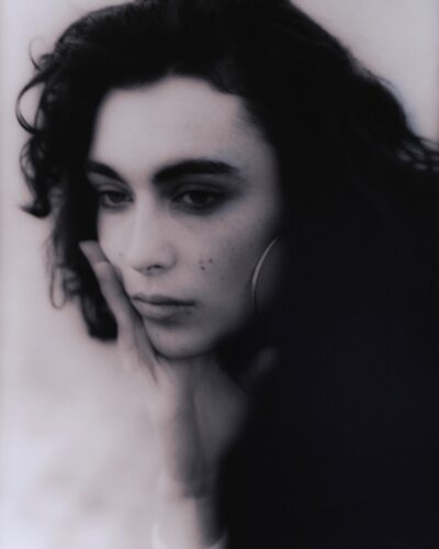 Analogue film photography portrait of a young woman with dark hair, thoughtfull and atmospheric black and white portraiture, captured on location in Barcelona, Spain, by Jeroen Busschers